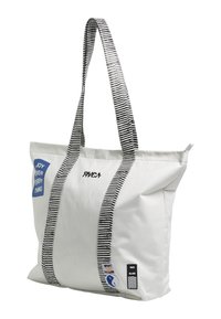 White tote bag with black and white striped handles. Features a blue patch with "JOY" text and brand logo. Smooth fabric, spacious design.