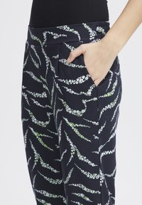 Navy pants with a floral pattern in white and green, featuring an elastic waistband and side pockets, smooth fabric texture.