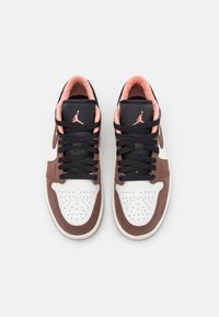 Pár hnědých, bílých a černých tenisek Air Jordan s růžovými detaily a černými tkaničkami, pohled shora na bílém pozadí.