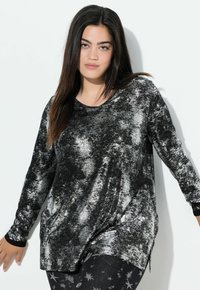 Zwart-zilver langsl sleeve top met een wervelend patroon, ronde hals en zwarte manchetten. Gecombineerd met zwarte legging met sterrenpatronen.