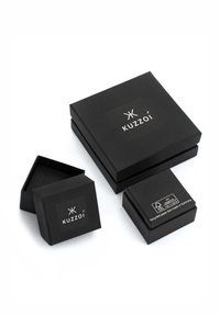 Mustat paperilaatikot eri kokoisina, joissa on logo ja kierrätystiedot. Laatikot ovat sileäpintaisia ja niissä on minimalistinen muotoilu.