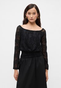 Μαύρο τοπ από δαντέλα με μακριά μανίκια, floral σχέδιο, off-the-shoulder λαιμόκοψη, συγκεντρωμένη μέση, στολισμένο με μια ταιριαστή μαύρη φούστα.