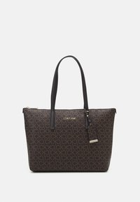 Borsa a spalla marrone con logo Calvin Klein, caratterizzata da un esterno decorato, manici neri doppi e una chiusura con zip con un'etichetta removibile.