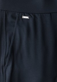 Marina träningsbyxor gjorda av mjukt tyg har en elastisk midja och sidofickor, med en silverfärgad "Street One" logotags.