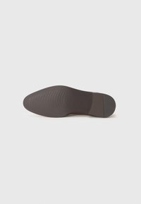 Semelle de chaussure en cuir brun avec un motif texturé, bout pointu et talon plat. Fini lisse avec un léger éclat et un detailing minimal.
