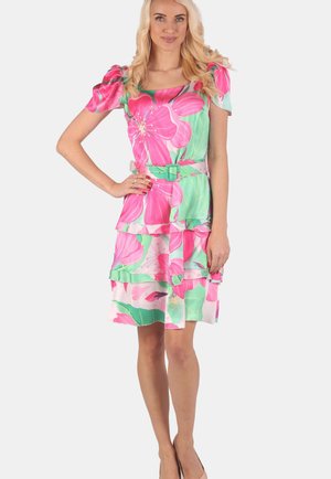 Blumenkleid mit quadratischem Ausschnitt, Puffärmeln und gestuftem Design. Mit lebhaften rosa und grünen Blumen auf einem weißen Hintergrund. Einschließlich eines passenden Gürtels.