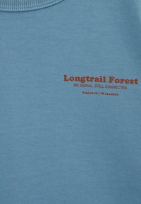 Hele sinine puuvillane t-särk, mis on varustatud soonilise ümara kaelusega ja punase kirjaga: "Longtrail Forest," "NO SIGNAL. STILL CONNECTED," ning koordinaatidega.