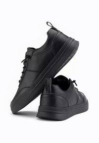 Baskets noires en cuir synthétique texturé, dotées d'un laçage à l'avant, d'un bout arrondi et d'une semelle en caoutchouc de profile bas.