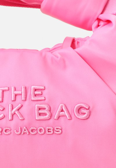Kütkava roosa kott, millel on kogutud disain, ümmarguse reljeefse tekstiga: "THE JACK BAG" ja "MARC JACOBS." Pehme, siledat kangast tekstuur.