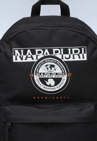 Zaino nero con un grande logo "NAPAPIJRI" e una grafica di ricerca antartica. Tessuto resistente, texture liscia, tasca frontale con zip.