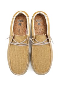 Zapatos de tela amarillos con una superficie texturizada, que presentan cordones beige, plantillas de corcho y un diseño simple y redondeado.