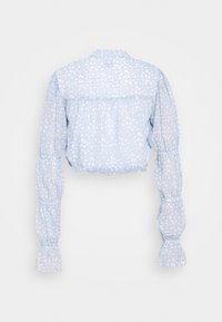 Blusa corta azzurra con maniche a sbuffo, decorata con un piccolo motivo floreale. Realizzata in un tessuto morbido con vita e polsini arricciati.
