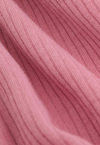 Rosa geripptes Strickgewebe mit einer weichen Textur, das unterschiedliche Dicken in den Rillen und glatten Bereichen zeigt und so ein subtil gemütliches Erscheinungsbild schafft.