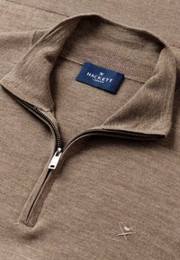Bruine gebreide zip-up trui met een hoge kraag, subtiele textuur en geborduurd logo op de borst. Etiket leest "HACKETT LONDON."