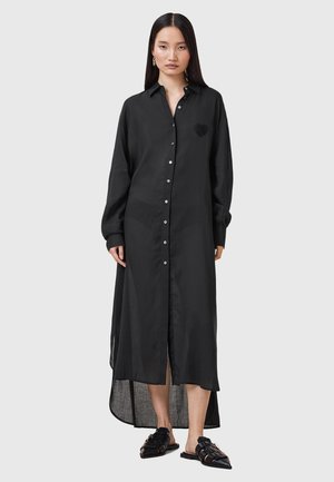 Abito camicia nero con maniche lunghe, spacco alto e dettaglio a cuore testurizzato sul lato sinistro del petto, realizzato in tessuto leggero.