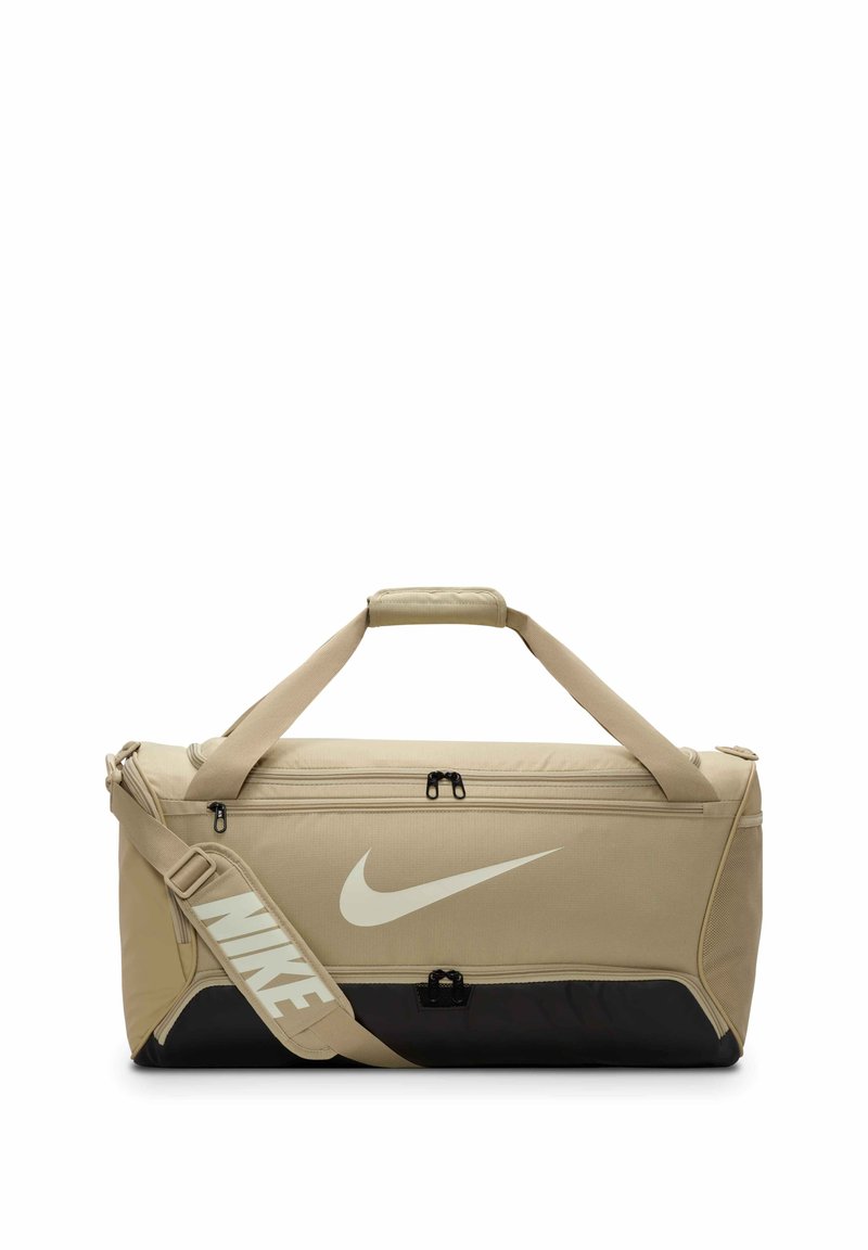 Beige sporttas met een zwarte basis, voorzien van dubbele ritssluitingen, bovenhandvatten en een verstelbare schouderriem met een wit Nike-logo.