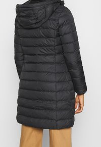 Abrigo acolchado negro con capucha, que presenta un diseño acolchado, mangas largas y un corte de longitud media. Textura suave con rayas verticales.