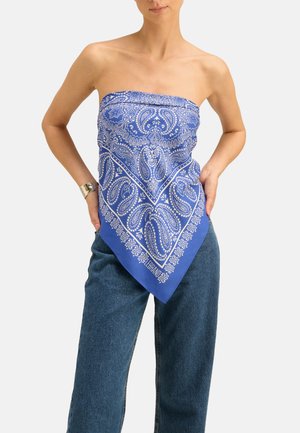 Niebieski top w stylu bandany z białym wzorem paisley, w kształcie trójkąta i gładkim materiale, noszony z dżinsami z wysokim stanem.