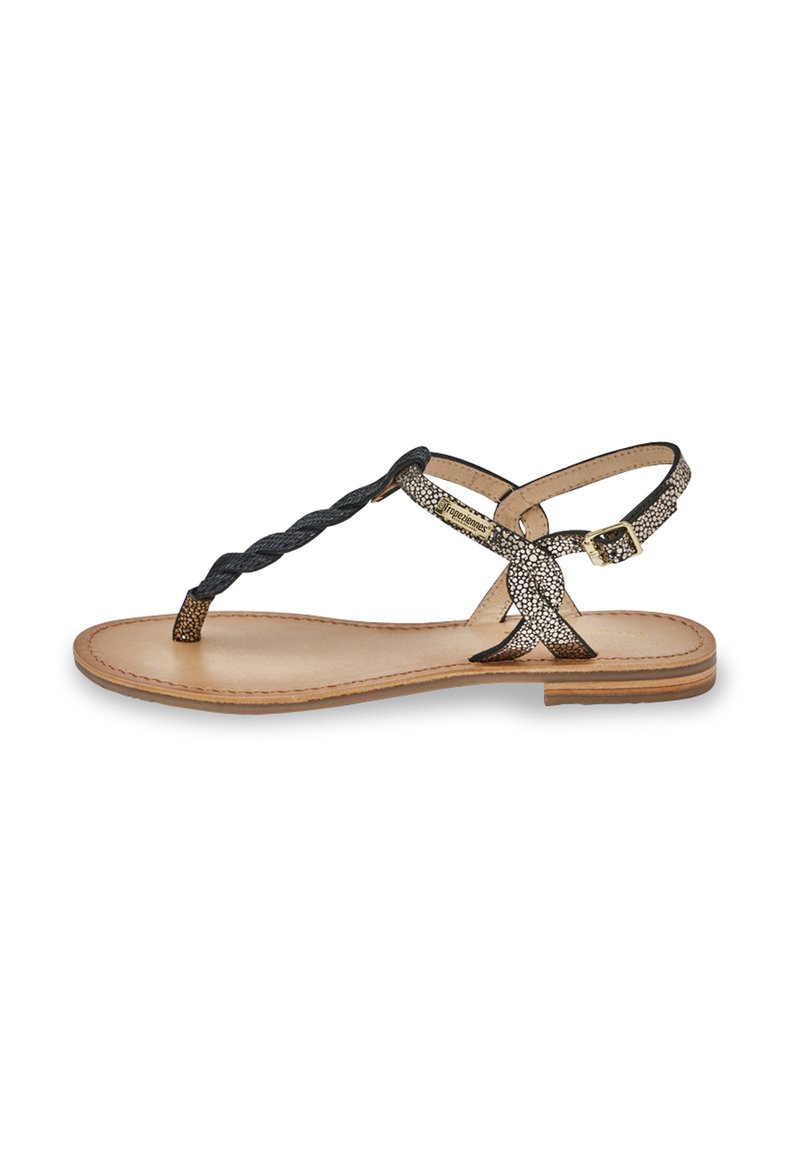 Sandalo piatto intrecciato nero e metallico con separatore per le dita, cinturino regolabile alla caviglia e suola in pelle marrone. Presenti dettagli decorativi testurizzati.