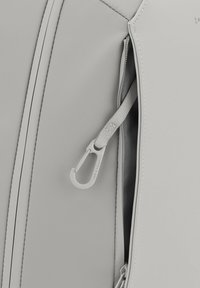 Grå zip-påse med texturerat material, en kontrasterande insida och en vit karbinhake på en tygslinga. Subtil sömdetalj.