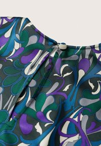 Blusa a maniche corte con uno sfondo scuro e audaci motivi swirling in viola, verde acqua e bianco. Include una chiusura con bottone rivestito di tessuto al collo.