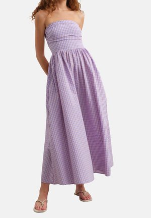 Strapless maxi-jurk in lichtpaars met geruit patroon, geplooid bij de taille en voorzien van een vloeiende, volle rok. Draagt eenvoudige sandalen.