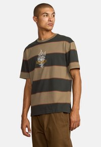 Camiseta de manga corta a rayas en verde oliva, beige y marrón, que presenta un diseño gráfico de rosa con acentos de llama en el pecho.