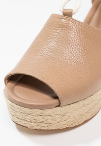 Sandale à plateforme beige en cuir avec bout ouvert, semelle en jute tressée et bride à la cheville.