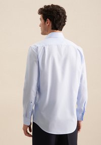 Lichtblauw overhemd met lange mouwen in een gladde stof, voorzien van een klassieke kraag, knoopmanchetten en een gebogen zoom. Heeft een discreet logodetail nabij de manchetten.