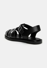 Sort sandal med flere stropper, en spænde ankelsnor, flad sål og glat, mat tekstur. Velegnet til afslappet brug.