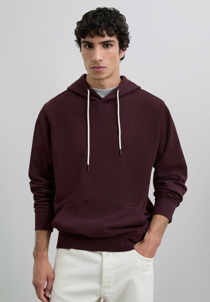 Sudadera color burdeos con capucha ajustable, bolsillo tipo canguro en la parte delantera y puños acanalados. Fabricada en un tejido suave de mezcla de algodón con una textura sutil.