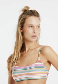 Top bikini a righe con colori pastello, caratterizzato da spalline sottili e un tessuto morbido. Include motivi a righe orizzontali e verticali.