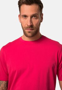 Roze katoenen t-shirt met korte mouwen, ronde hals en een gladde textuur. Het shirt heeft geen zichtbare patronen of accenten.