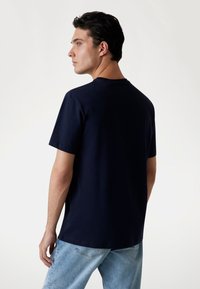 Marineblaue Baumwoll-T-Shirt mit kurzen Ärmeln, Rundhalsausschnitt und lockerer Passform. Die Rückseite hat ein glattes, ungeschmücktes Design.