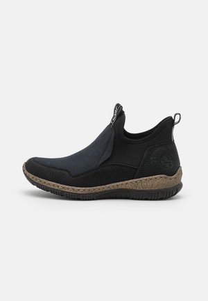Zapatos negros sin cordones con acentos texturizados, panel de ante azul y suela de goma. Cuentan con una pestaña trasera para facilitar el uso y una plantilla acolchada.