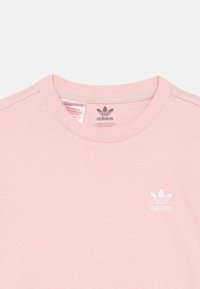 Pink cotton t-shirt with a crew neckline, featuring a subtle white embroidered Adidas logo on the left chest. Smooth texture.