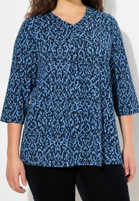 Blå och svart mönstrad topp med V-ringning och trekvartsärmar, med en texturerad design och en lös passform.