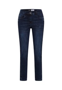 Tmavě modré džíny z denimu s úzkým střihem, pěti kapsami a zapínáním na knoflíky. Jemné opotřebení na přední straně přidává jemnou texturu.