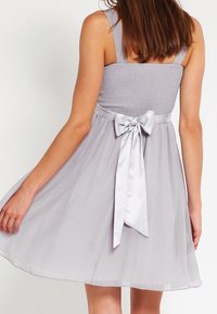 Světlé fialové šaty s nařaseným živůtkem, širokými ramínky a rozšířenou chiffonovou sukni, se saténovou mašlí na zadní části.