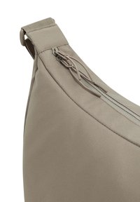 Borsa di tessuto beige con forma curva, dotata di chiusura con zip e superficie testurizzata. La tracolla è rinforzata per garantire durata.