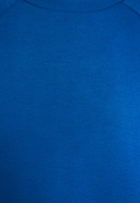 Blaues Strickgewebe mit glatter Textur, ausgestattet mit einem Rundhalsausschnitt und gerippten Details an den Rändern. Keine sichtbaren Muster oder Akzente.