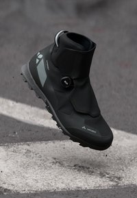 Melna ūdensizturīga velosipēdu kurpe ar augstu potītes dizainu, BOA aizvēršanas sistēmu un atstarojošām akcentiem, ar strukturētu gumijas zoli.