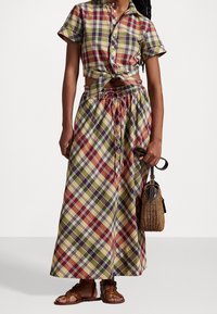 Plaid set featuring a knotted short-sleeve top and a long, drawstring skirt. Made of cotton with colors in red, green, yellow, and blue.