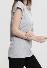 T-shirt grigio a maniche corte con una vestibilità comoda, texture sottile e scollatura rotonda, abbinato a pantaloni neri.
