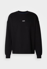Sweat-shirt noir à manches longues avec col rond, petit logo rectangulaire blanc "HUGO" centré sur la poitrine sur fond uni.