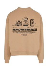Felpa beige con scollo a girocollo, con una grafica nera che illustra alimenti per la colazione: panino, caffè e succo d'arancia, oltre a del testo.