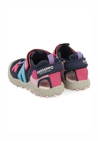 Sandalias Gioseppo en navy y rosa con la parte trasera abierta, correa de gancho y bucle, y paneles laterales multicolores. Suela de goma texturizada con acentos en rosa.