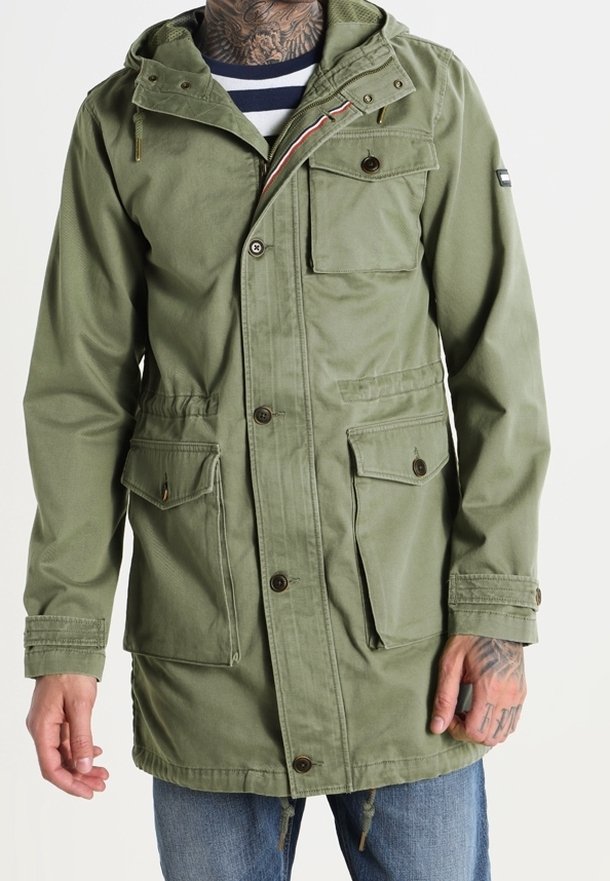 Parka verte avec capuche, fermeture à boutons à l'avant, poches poitrine et latérales, et taille à cordon. Dotée d'une doublure intérieure rayée.