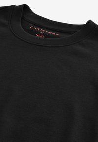 Black sweatshirt with a crew neckline. Soft texture, featuring red text "CHRISTMAS AT NEXT" on the collar. Minimalist design.