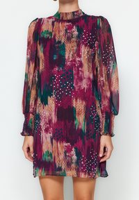 Robe à manches courtes en tissu transparent violet avec des motifs abstraits colorés et des accents blancs. Comprend un col montant et des poignets élastiqués.